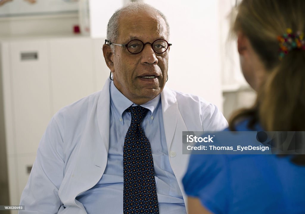 Concerned Doctor Meeting with His Patient "Mature Black medical doctor with a serious expression on his face, speaks to a female patient in his office. Horizontal shot." Adult Stock Photo