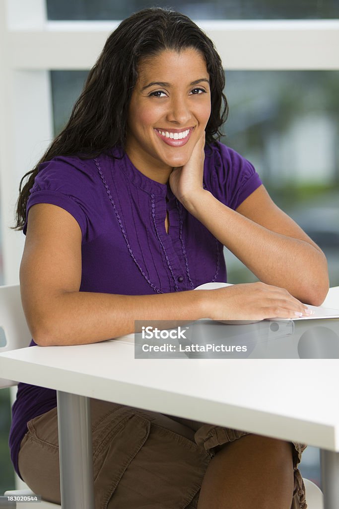 Sorrindo feminino, sentado atrás de uma escrivaninha com a reserva - Foto de stock de 30-34 Anos royalty-free
