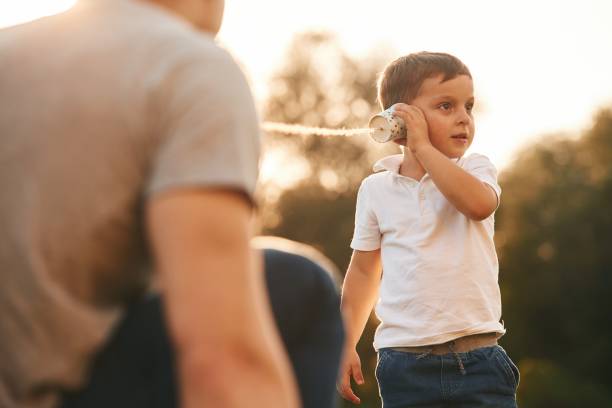 istock Fun, holding and using string can phone. Father and little son are playing outdoors 1830206560