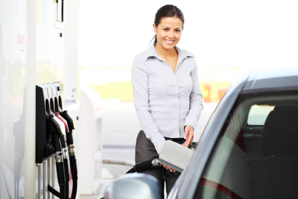 bellissima ragazza versato nel serbatoio carburante auto per le pompe. - tank top foto e immagini stock