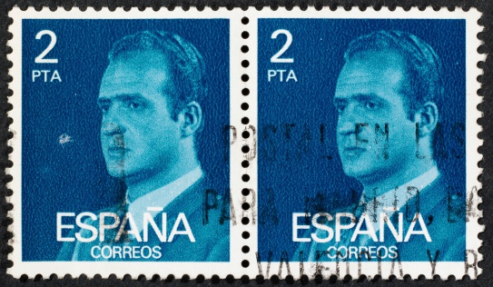 two Spanish postage stamps on black background