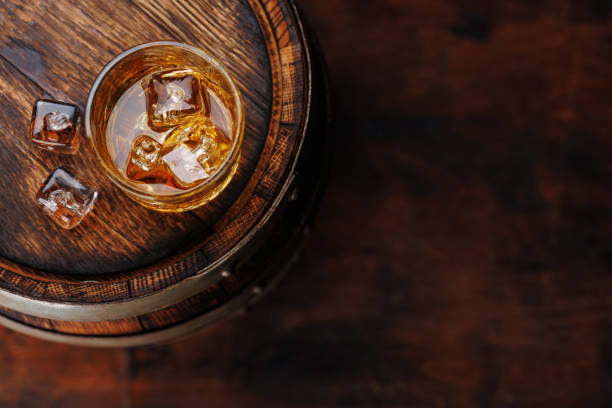 istock Whiskey glass with ice on a rustic barrel, a classic sip 1830207813