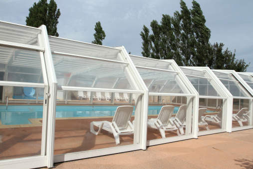 Swimming pool with a sliding roof cover enclosure