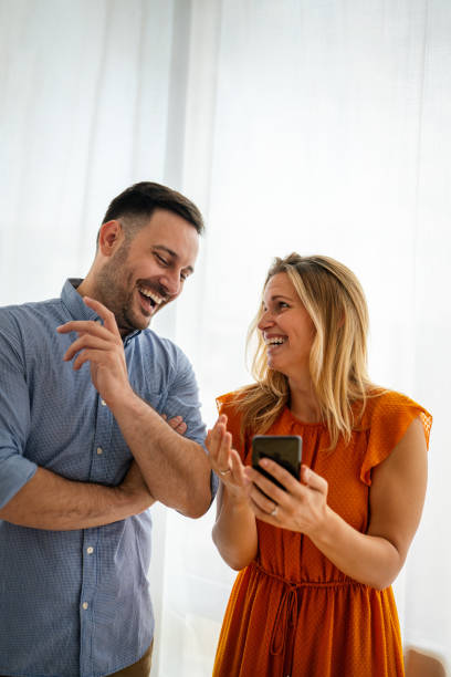 istock Smiling couple embracing while using a smartphone. People sharing social media on mobile phone. 1830217918