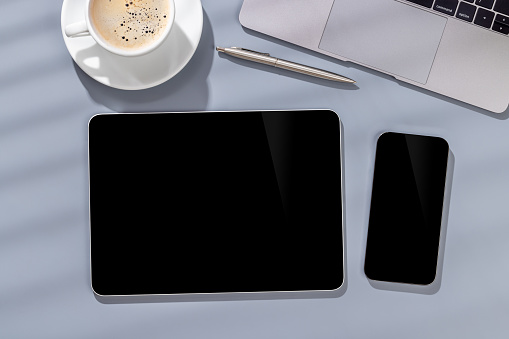 Blank black screen smartphone and tablet on a desk, perfect for your design mockup