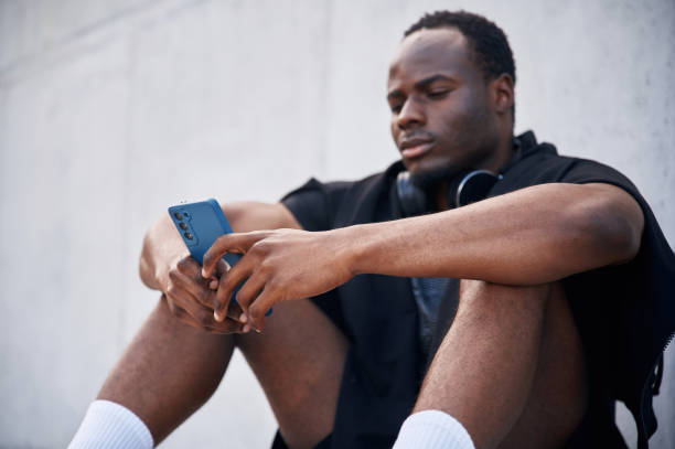 istock Sitting by the white wall. Handsome black man is posing outdoors at daytime 1830219986