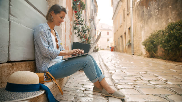 SLO MO Open-Air Office: Woman Works with Laptop on Cobblestone Steps in Rovinj's Historic Alley