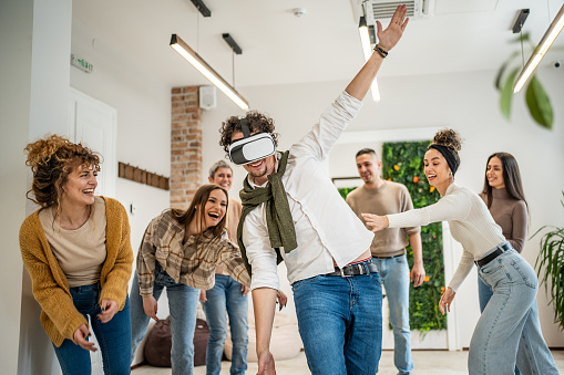 A group of mixed-age freelancers people relax with a game with VR glasses in a party room