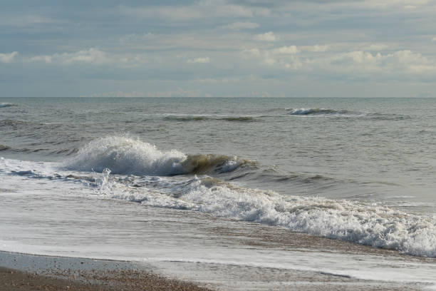 istock Foamy sea waves roll on the sandy daytime beach 1830228950