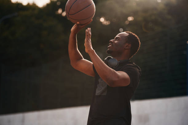 istock Sunlight outdoors. Young black man is with basketball ball 1830236406