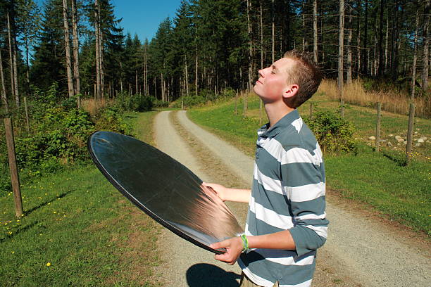 teenaged boy stands sunning himself with photography reflector stock photo