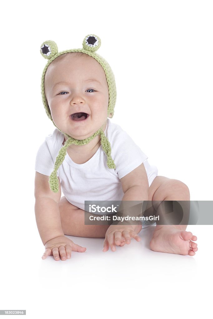 Cute Baby Wearing Knit or Crochet Frog Hat "Cute baby sitting on white floor background, wearing a onesy and a knit or crochet green frog hat." 6-11 Months Stock Photo