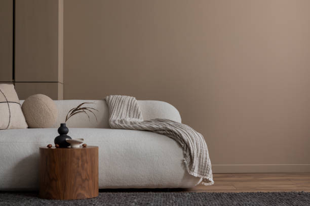 istock Minimalist composition of warm living room interior with copy space, white boucle sofa, gray plaid, beige pillow, wooden coffee table, brown shelf, and personal accessories. Home decor. Template. 1830240117