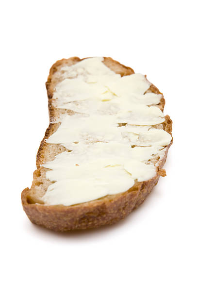 Slice of bread served with butter. White background. Shallow depth of field.