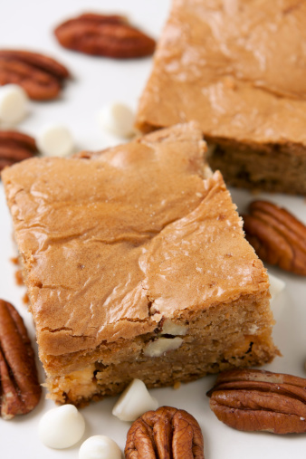 White chocolate brownies called blondies nestled among white chocolate chips and pecans.