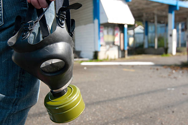 Man holding a gas mask at an abandoned car wash.