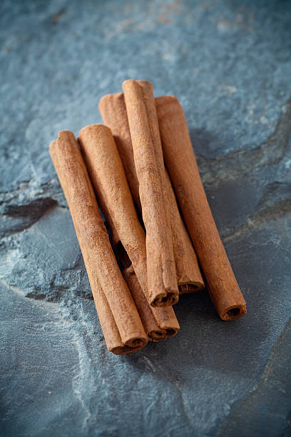 Cinnamon Sticks "Flavorful Cinnamon sticks on stone, shallow dof" cinnamon stock pictures, royalty-free photos & images