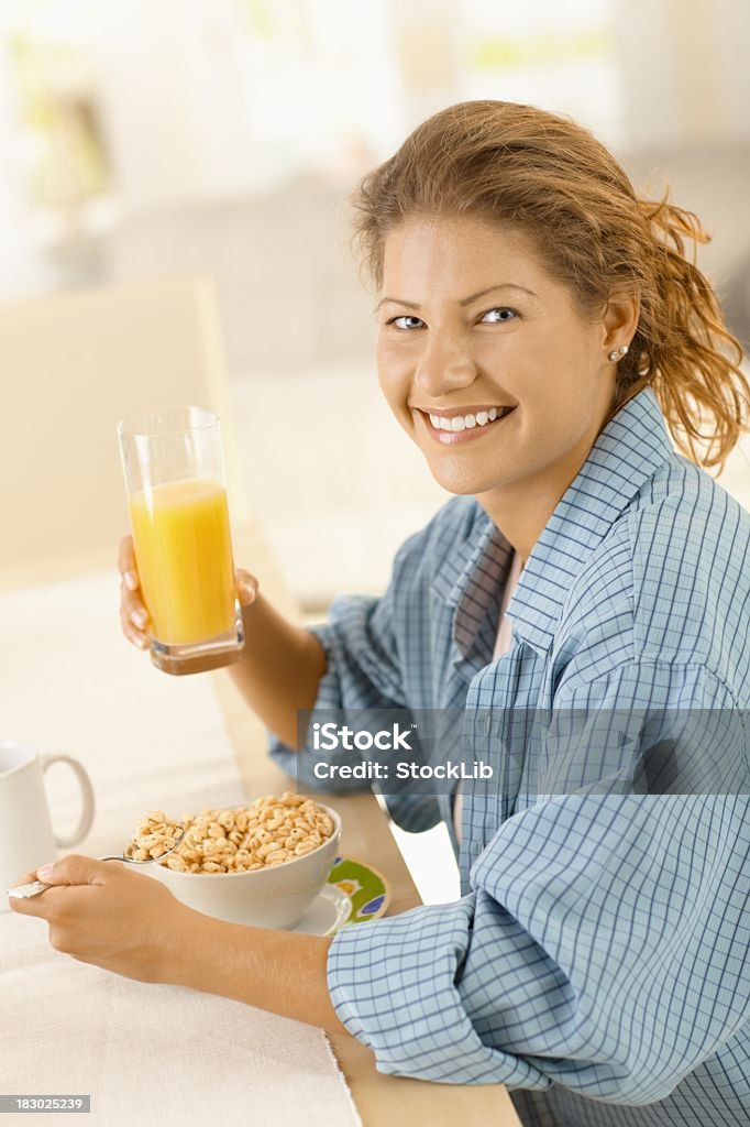 Jeune femme ayant un petit déjeuner dans la cuisine - Photo de Adulte libre de droits