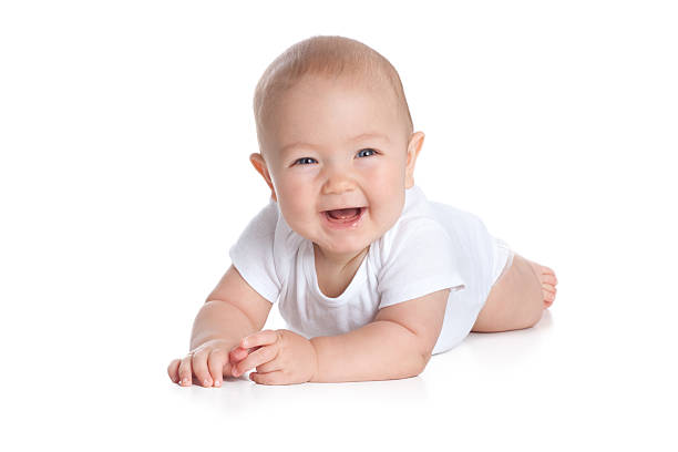 Happy Seven Month Old Baby on White Background "Cute baby lying on stomach on white floor background, wearing a onesy and smiling big." crawling photos stock pictures, royalty-free photos & images