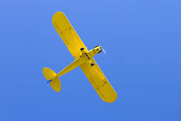 istock Yellow Single Engine Airplane from Below against Clear Blue Sky 183025971