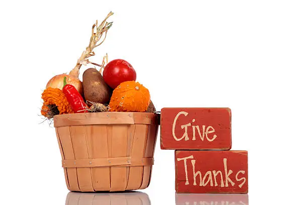 Blocks painted with the words give thanks a white background with  a basket of fresh produce.