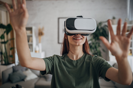 Young woman having fun with virtual reality headset in living room at home.
