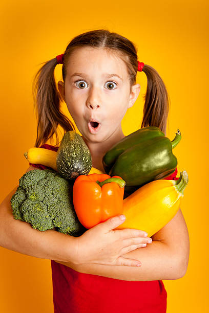 istock Surprised Young Girl Holding Vegetables, Bell Peppers, Broccoli, Squash, Zucchini 183026620