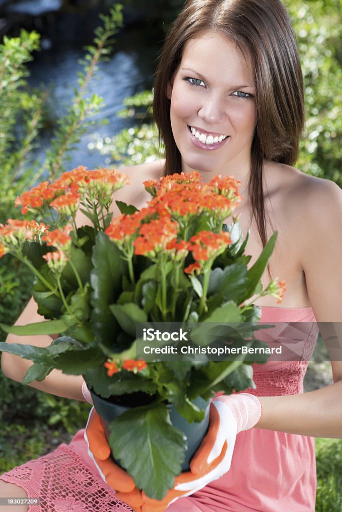 Smiling woman holding orange kalanchoe Smiling woman gardening 20-24 Years Stock Photo