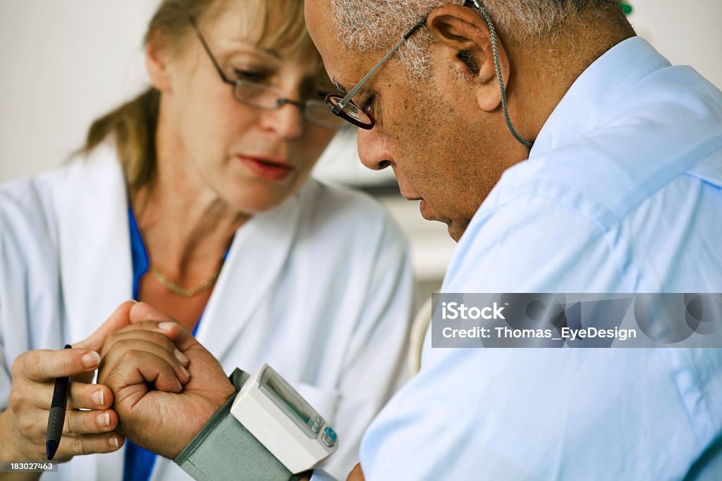Medico controllando la pressione del sangue di Suo paziente - Foto stock royalty-free di Misuratore di pressione sanguigna