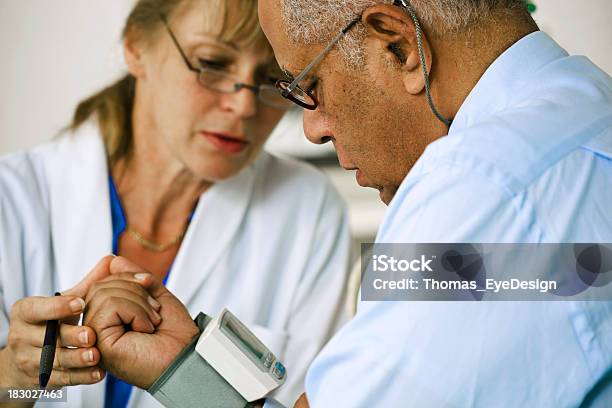 Medico Controllando La Pressione Del Sangue Di Suo Paziente - Fotografie stock e altre immagini di Misuratore di pressione sanguigna