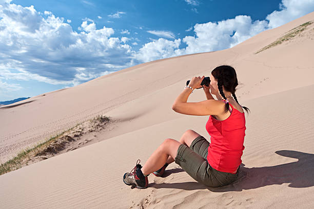 istock Young woman is looking through a binoculars on the desert 183027652