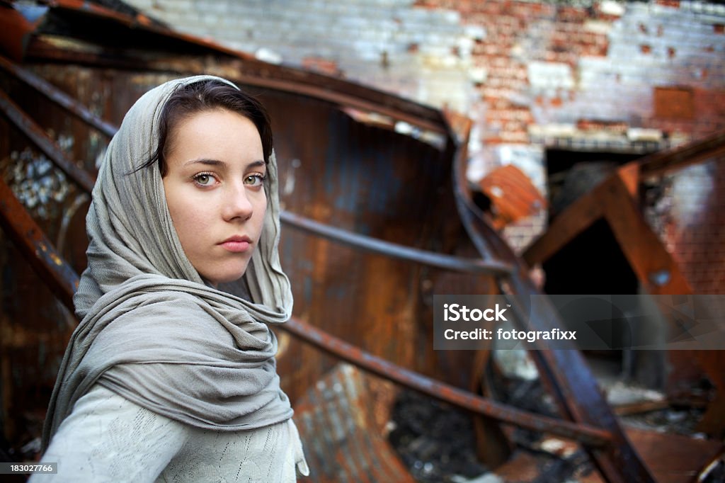 young woman with headscarf in front of a destroyed building young woman with proud glance and a headscarf in front of a destroyed building Kurdish Ethnicity Stock Photo