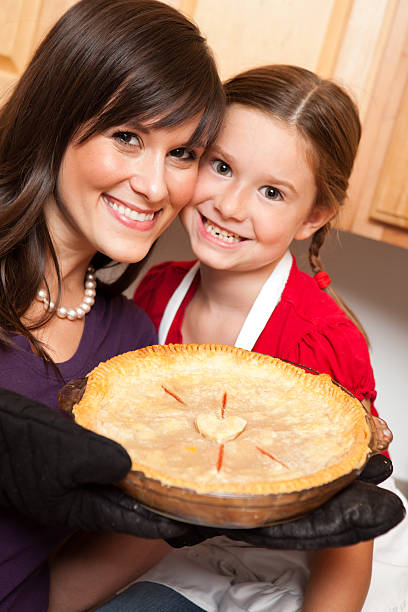 Happy Mother and Daughter Holding Cherry Pie in Kitchen