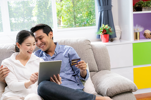 A happy couple using a credit card to make online purchases at home.
