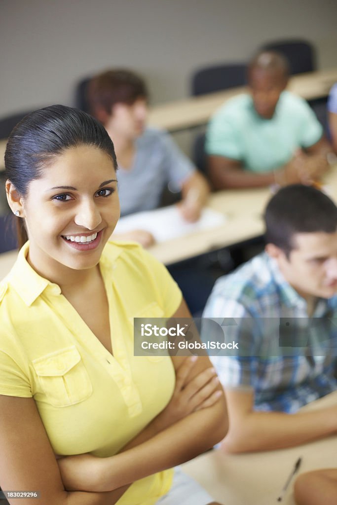 Chica joven con las manos doblado y classmate de desenfoque de fondo - Foto de stock de 20 a 29 años libre de derechos