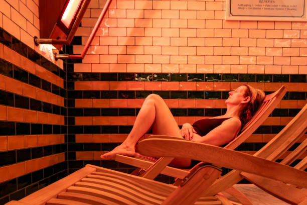Infra-red sauna A woman sits in a wooden deck chair and enjoys the benefits of an infra red sauna swedish sauna stock pictures, royalty-free photos & images