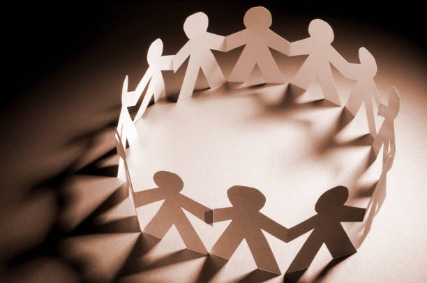 istock Circle of paper chain people holding hands in spotlight 183030515