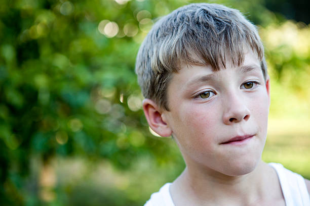 istock Young boy contemplates thoughts in a park after playing 183030856