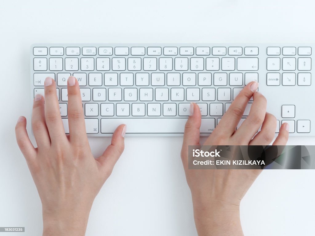 Mani femminili digitando sulla tastiera di un computer bianco - Foto stock royalty-free di Digitare