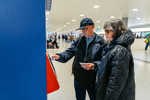 Senior couple buying train tickets using smartphone at the train station in Zurich, Switzerland.