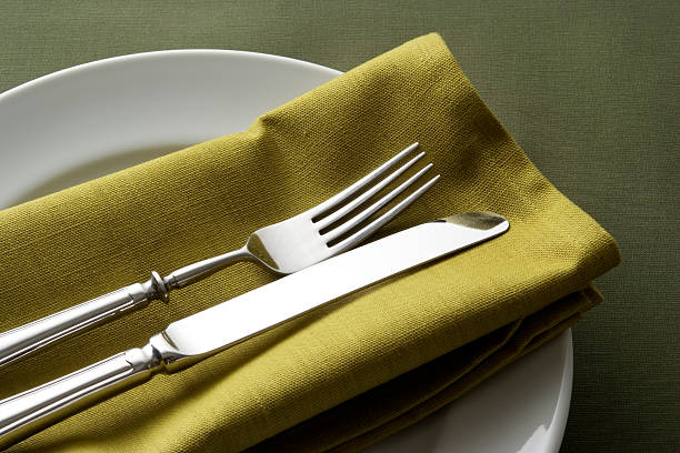 istock White plate with silverware and green napkin on green tablecloth 183031519