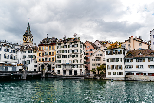 The Limmat river with old buildings and St. Peter's church in the background in Zurich, Switzerland.