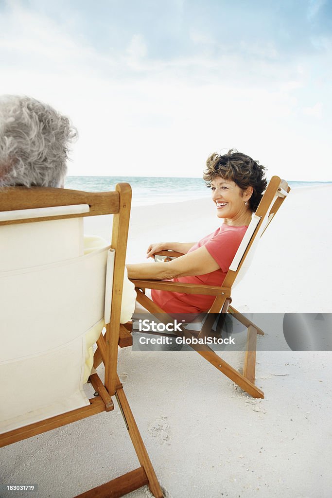 Relaxed smiling mature couple enjoying their vacation on beach Relaxed smiling senior man and woman enjoying their vacation on beach 50-59 Years Stock Photo