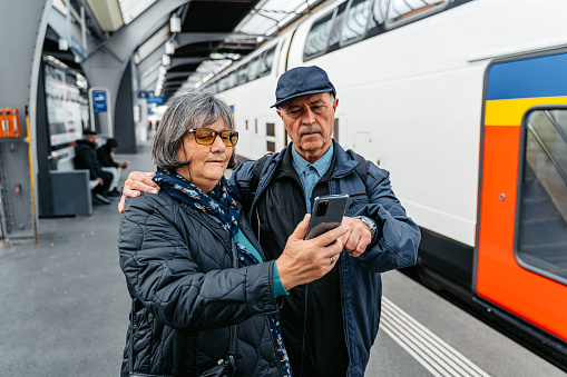 Senior tourist couple checking information using smartphone at Zurich train station in Switzerland.