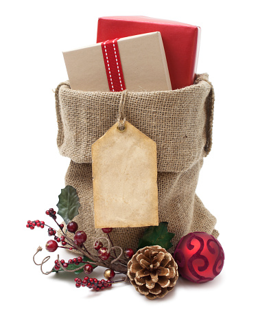 A burlap sack filled with wrapped Christmas gifts. Blank gift tag for your copy.