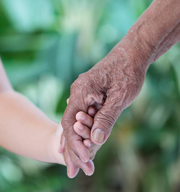 Old and young holding hands stock photo