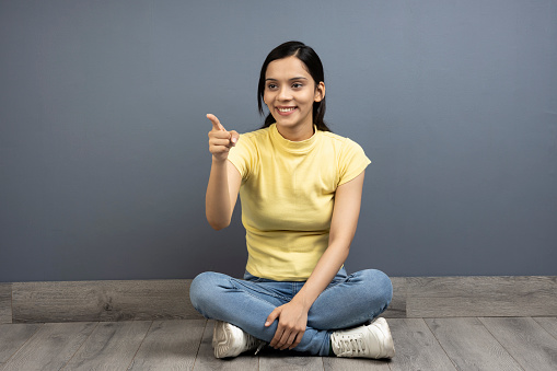 Young woman sitting and pointing stock photo