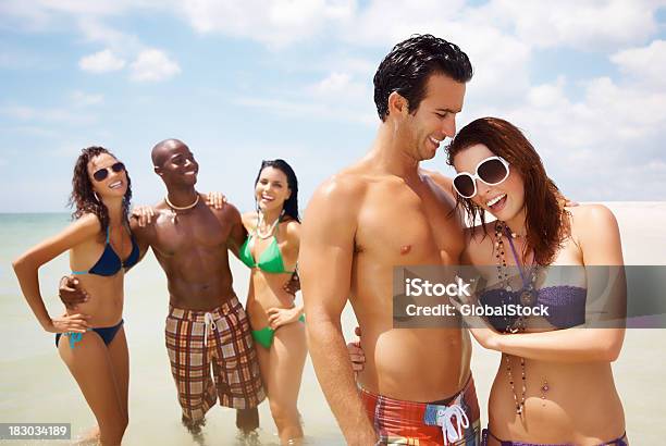 Happy Young Couple With Friends Enjoying On Beach Stock Photo - Download Image Now - 20-29 Years, 30-39 Years, Adult