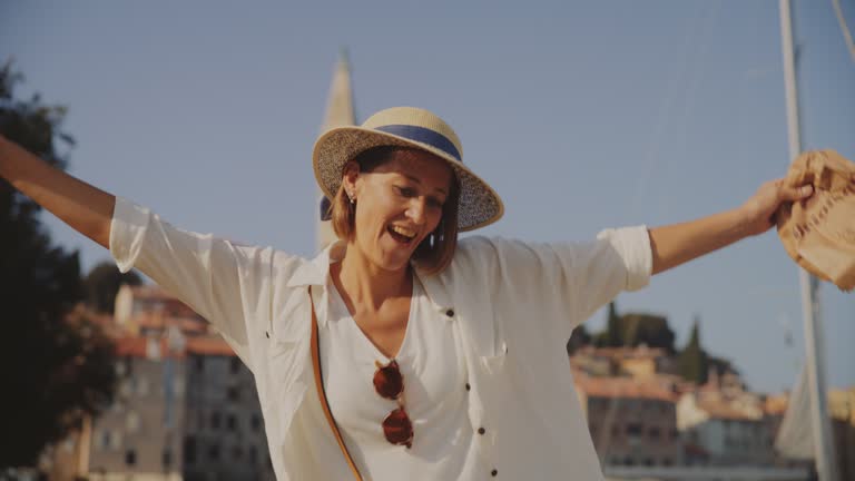 SLO MO Breezy Bliss: Woman's Joyful Jumps with Arms Outstretched at Rovinj's Promenade