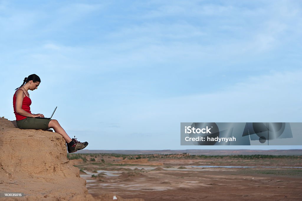 Jeune femme avec ordinateur portable sur la roche - Photo de 20-24 ans libre de droits